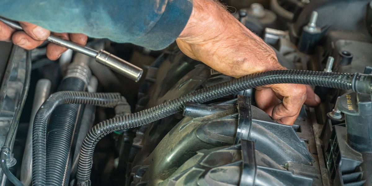 A mechanic's hands working a socket wrench under the hood of a car